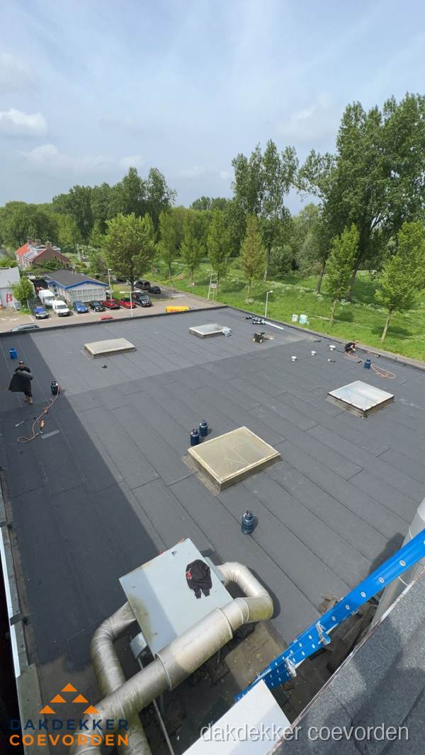 Dakdekker aan het werk op groot plat dak met bitumen in Coevorden