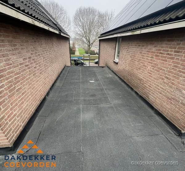Plat dak met bitumen dakbedekking tussen bakstenen muren in Coevorden Plat dak met bitumen dakbedekking tussen bakstenen muren in Coevorden